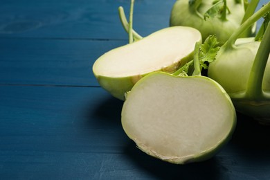 Photo of Whole and cut kohlrabi plants on blue wooden table