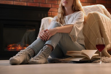 Photo of Beautiful young woman resting near fireplace at home, closeup