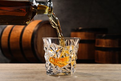 Pouring whiskey into glass from bottle on wooden table