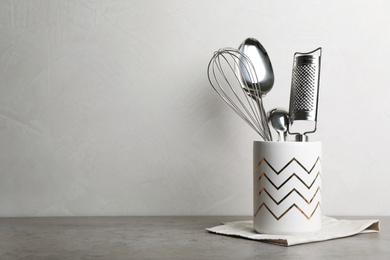 Holder with kitchen utensils and napkin on table. Space for text