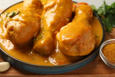 Photo of Tasty chicken curry and ingredients on wooden board, closeup