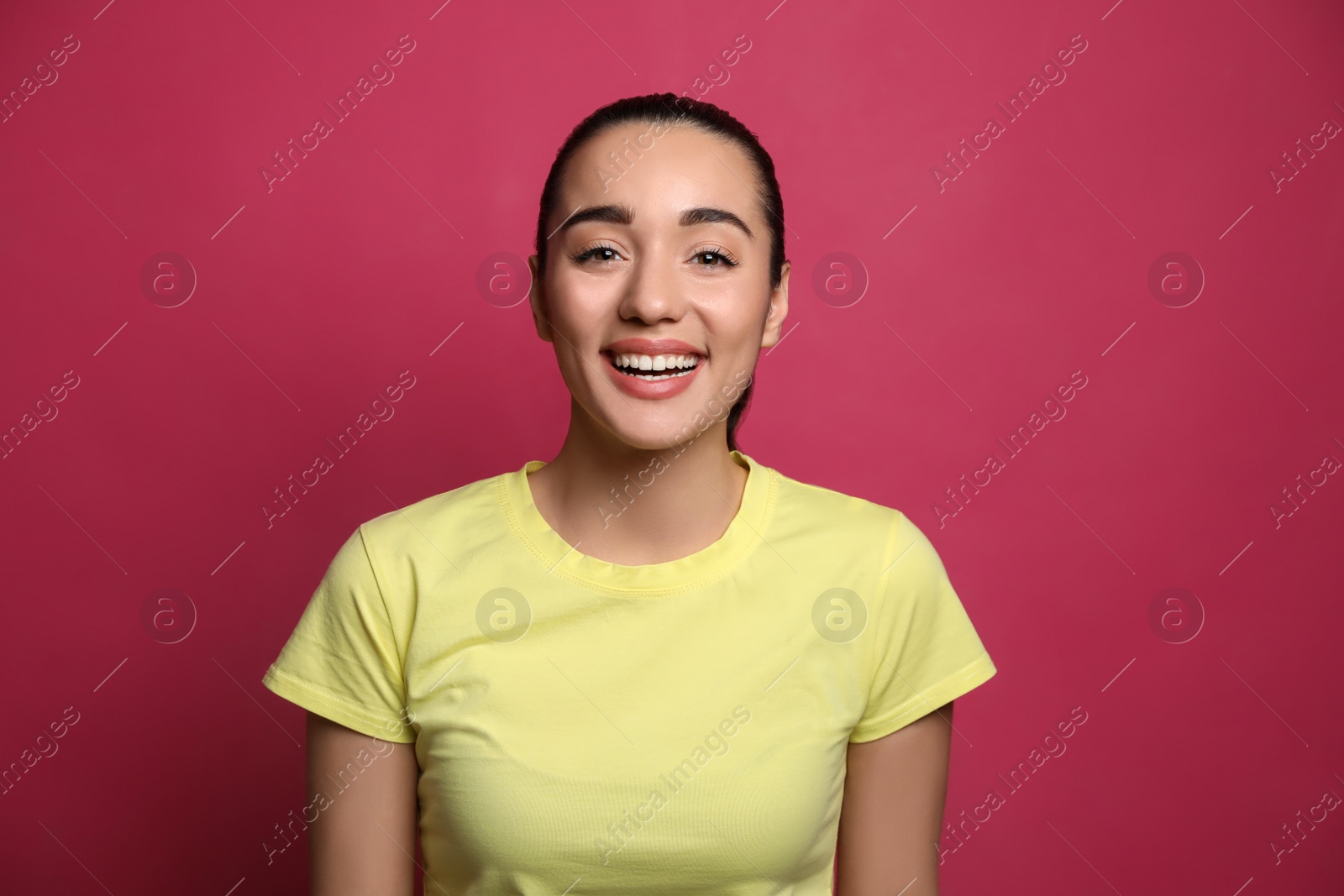 Photo of Beautiful young woman laughing on maroon background. Funny joke