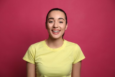 Beautiful young woman laughing on maroon background. Funny joke