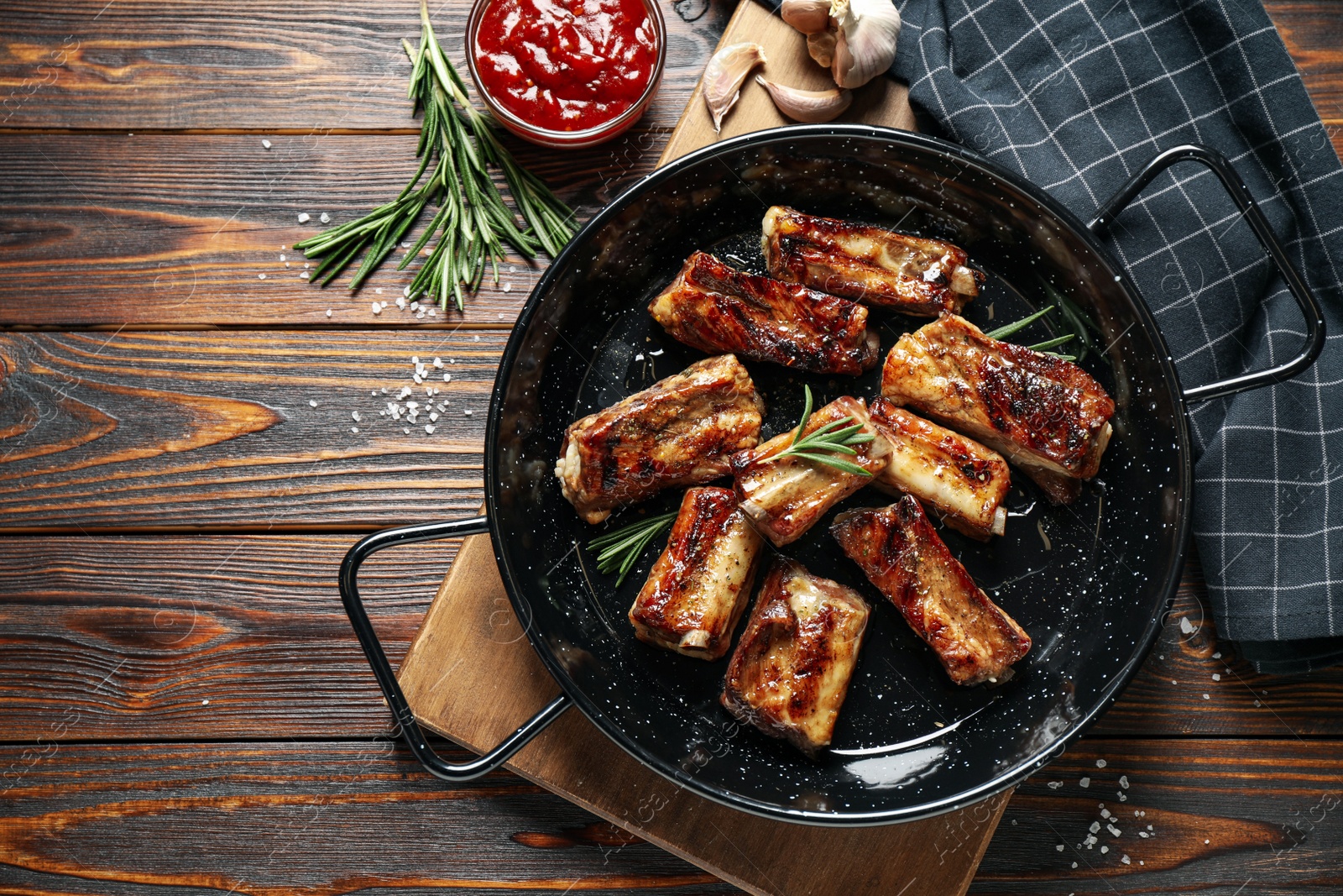 Photo of Delicious grilled ribs served on wooden table, flat lay