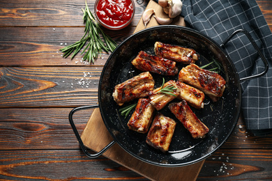 Photo of Delicious grilled ribs served on wooden table, flat lay