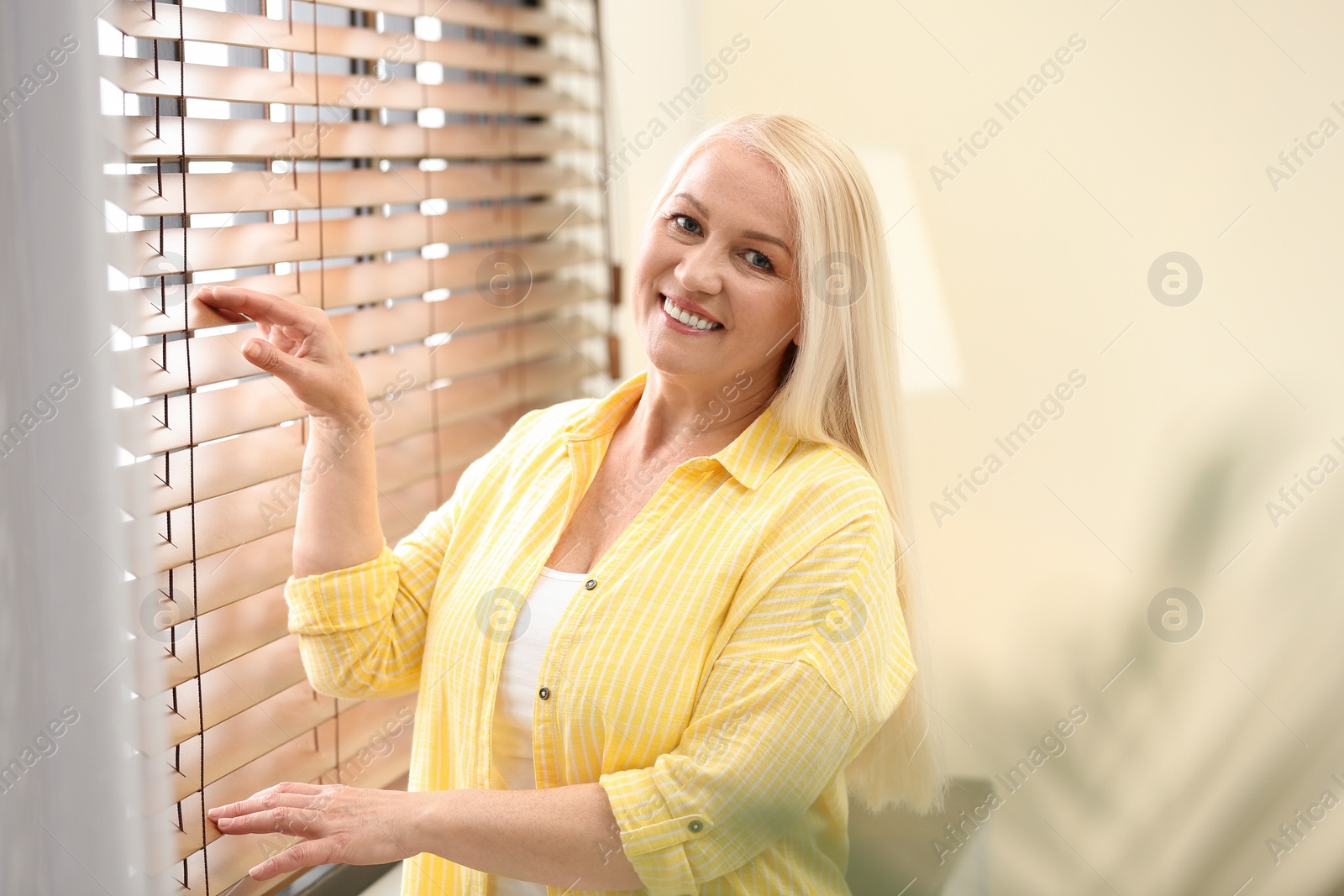 Photo of Portrait of happy mature woman near window indoors