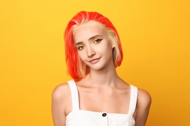 Photo of Beautiful young woman with bright dyed hair on orange background