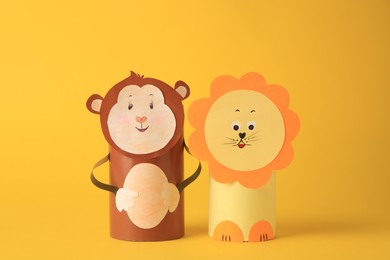 Photo of Toy monkey and lion made from toilet paper hubs on yellow background. Children's handmade ideas