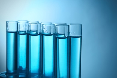 Photo of Test tubes with liquid against color background, closeup. Laboratory analysis