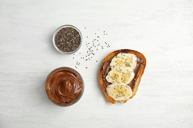 Photo of Flat lay composition with tasty toast, chocolate paste and chia seeds on white wooden background, top view