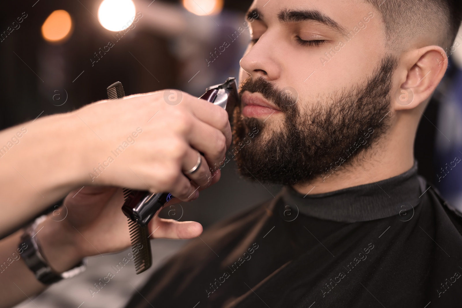 Photo of Professional hairdresser working with client in barbershop, closeup