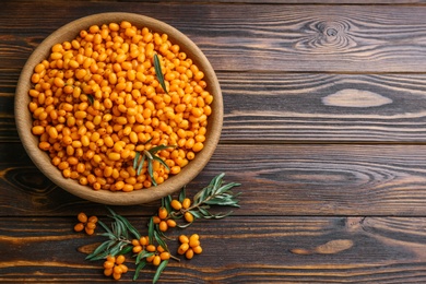 Photo of Fresh ripe sea buckthorn on wooden table, flat lay. Space for text