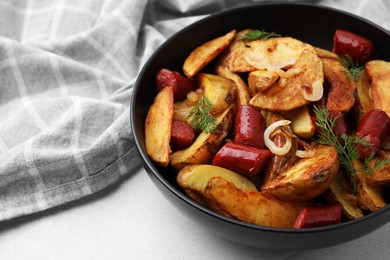 Photo of Delicious baked potato with thin dry smoked sausages, onion and dill in bowl on gray table, closeup