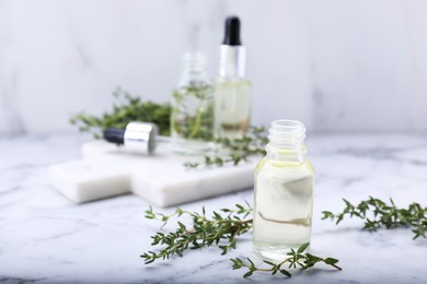 Photo of Thyme essential oil on white marble table, space for text