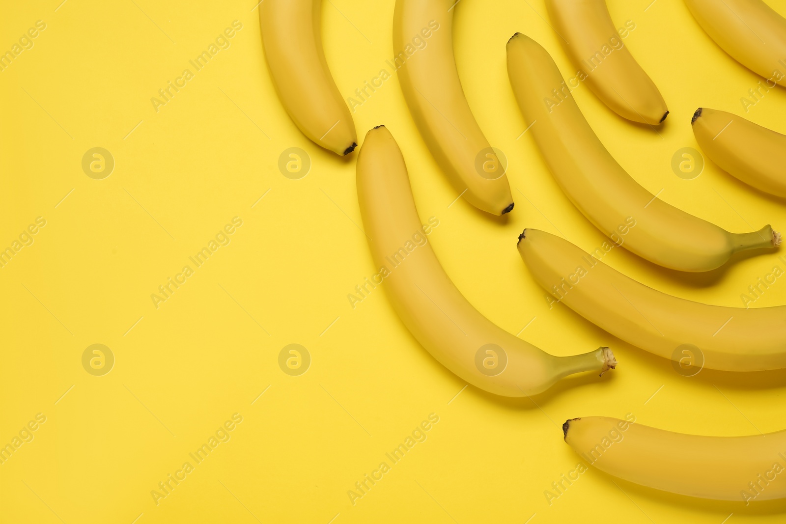 Photo of Ripe sweet bananas on yellow background, flat lay. Space for text
