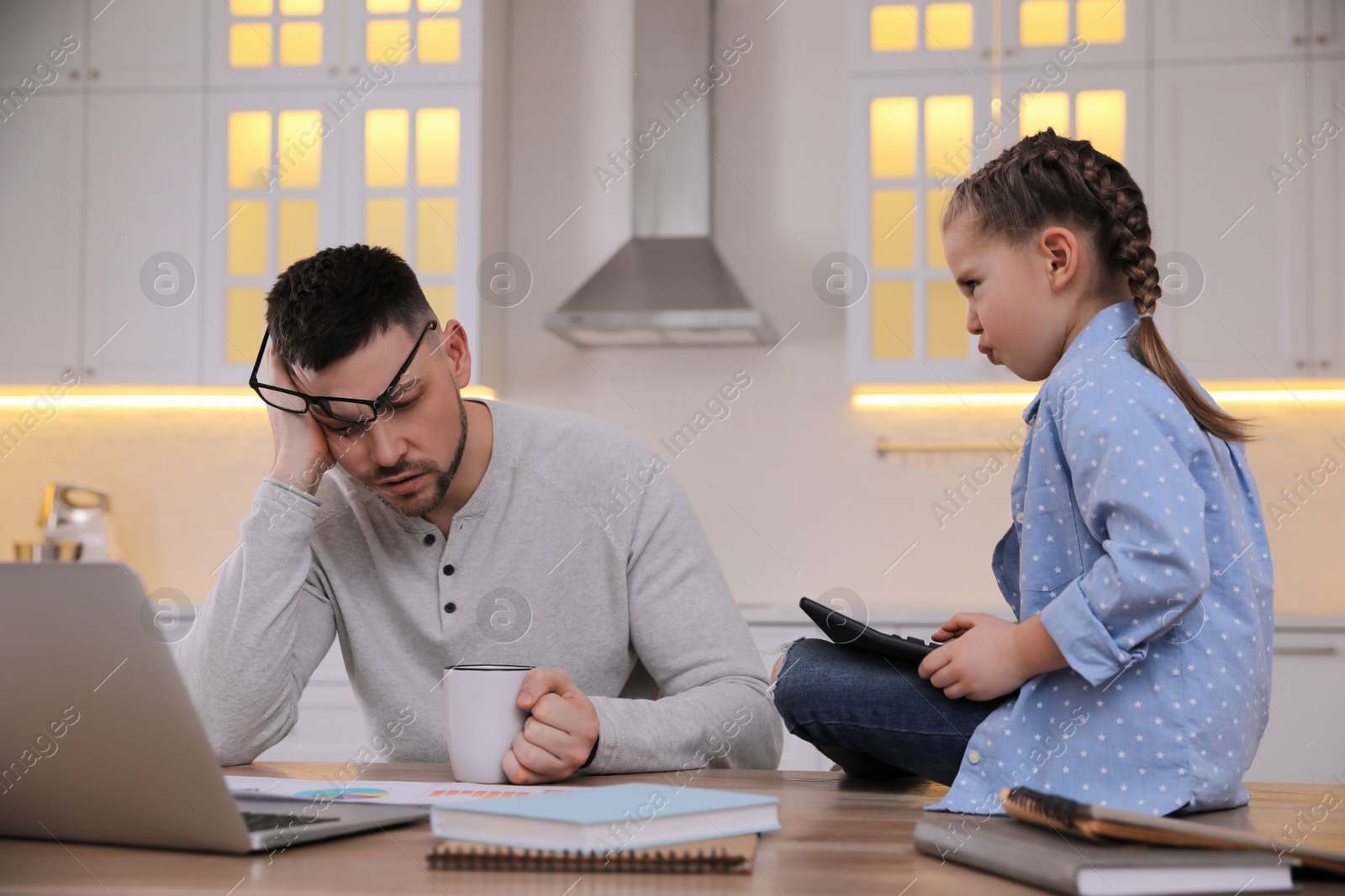 Photo of Overwhelmed man combining parenting and work at home