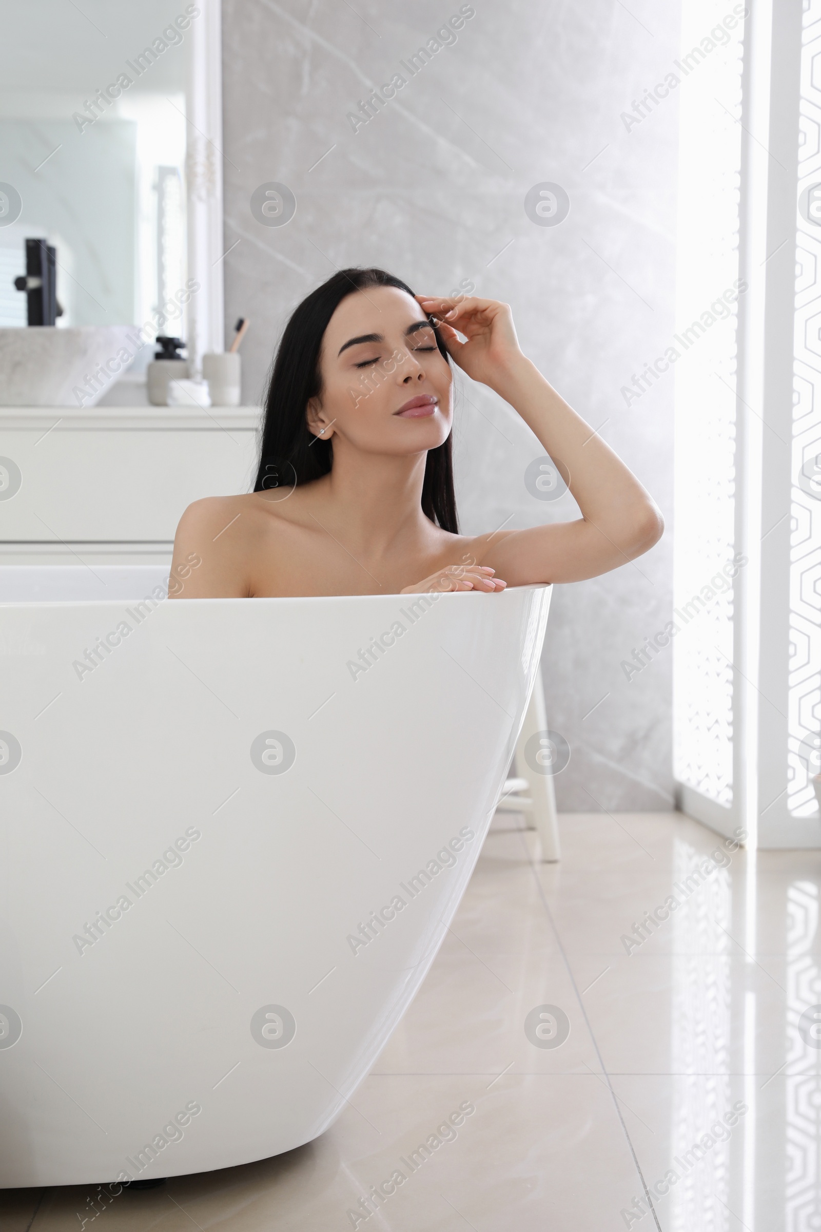 Photo of Beautiful young woman relaxing in bathtub at home