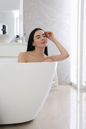 Beautiful young woman relaxing in bathtub at home