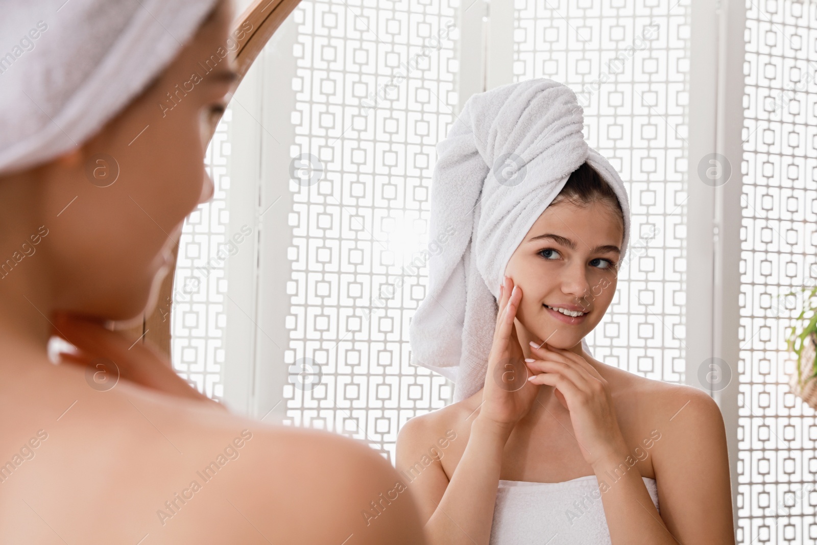 Photo of Beautiful teenage girl with towels near mirror in bathroom