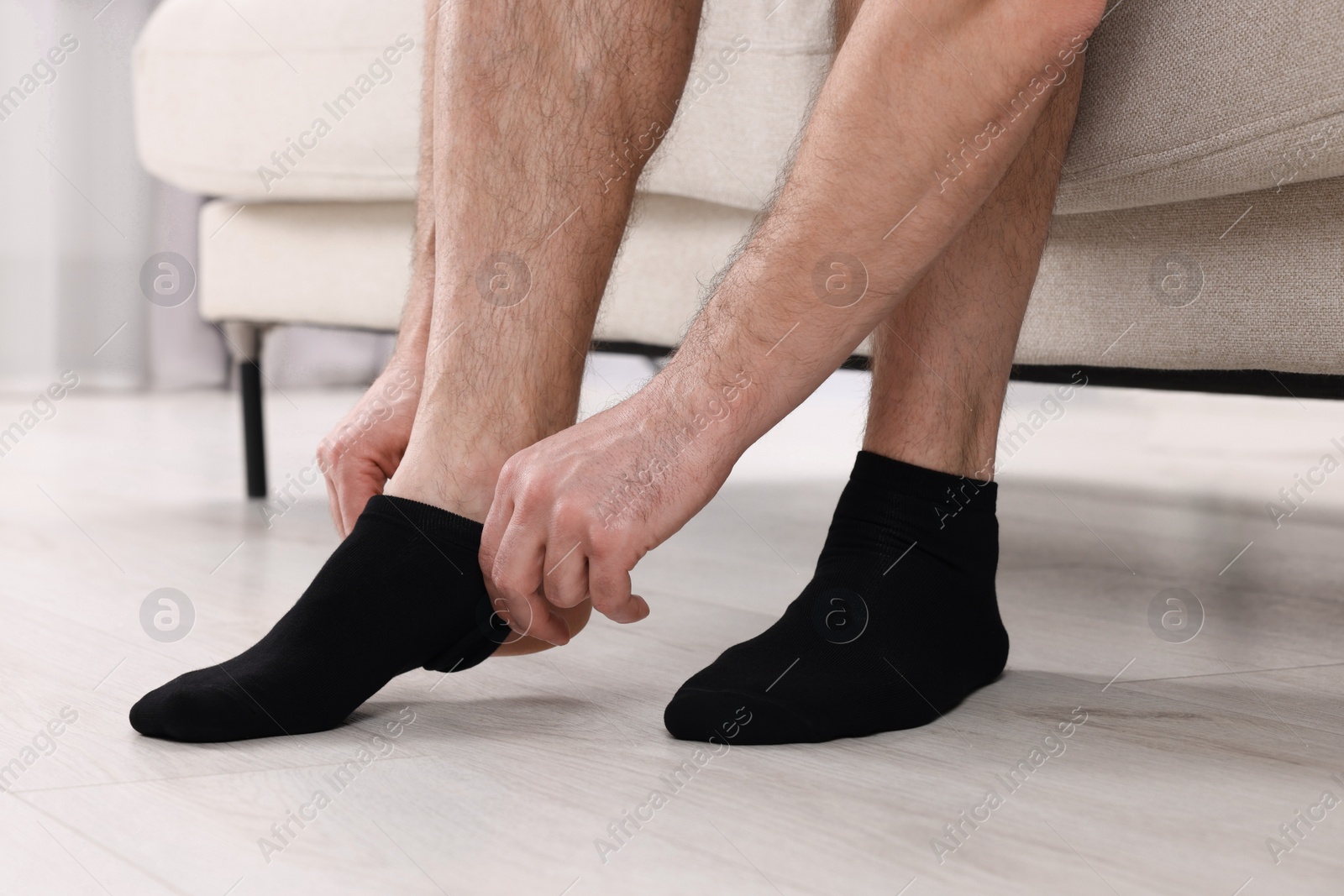 Photo of Man putting on black socks at home, closeup