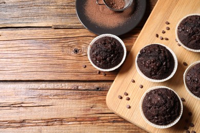 Photo of Tasty chocolate muffins on wooden table, flat lay. Space for text