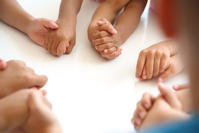 Little children holding hands at table, closeup. Unity concept