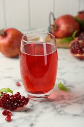 Photo of Tasty pomegranate juice in glass and fresh fruits on white marble table