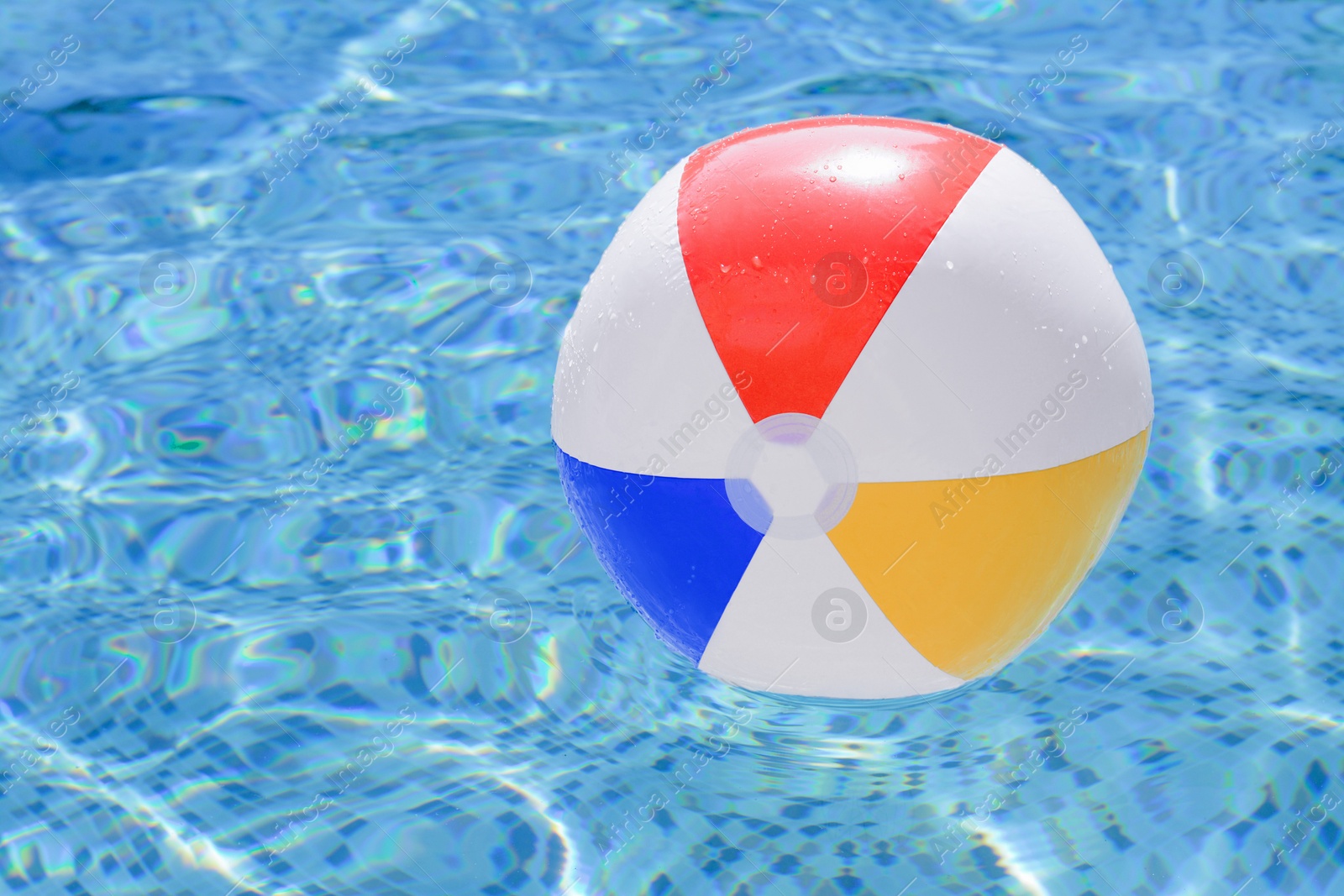 Photo of Inflatable beach ball floating in swimming pool, space for text