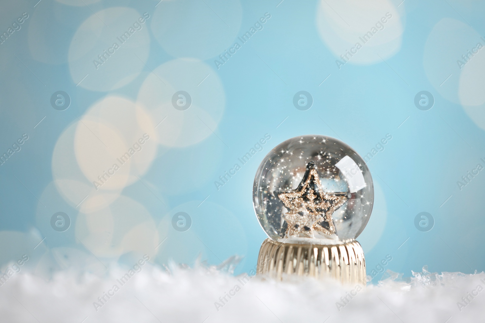 Photo of Beautiful snow globe with stars against blurred Christmas lights. Space for text