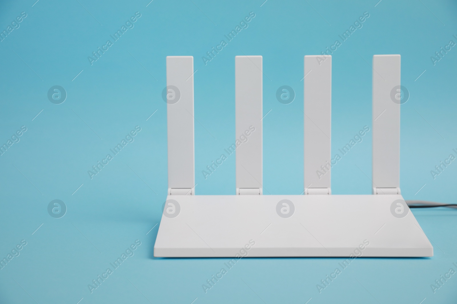 Photo of Modern Wi-Fi router on light blue background. Space for text