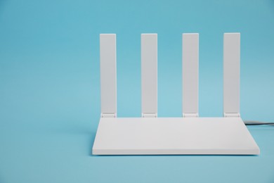 Photo of Modern Wi-Fi router on light blue background. Space for text