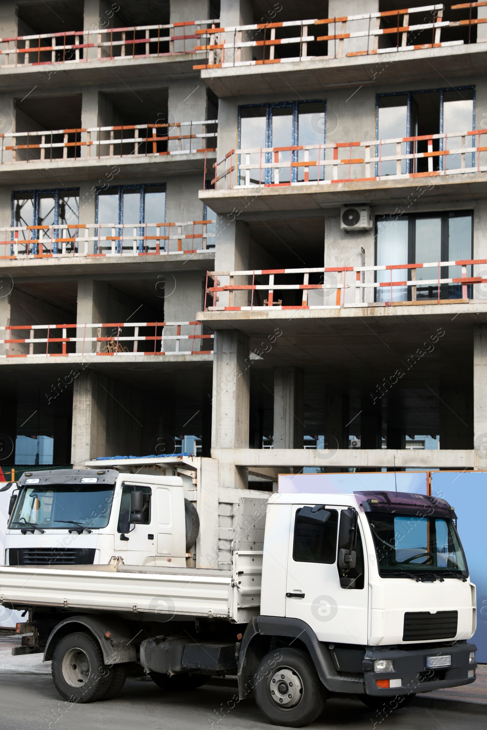 Photo of Construction site with unfinished building and trucks outdoors