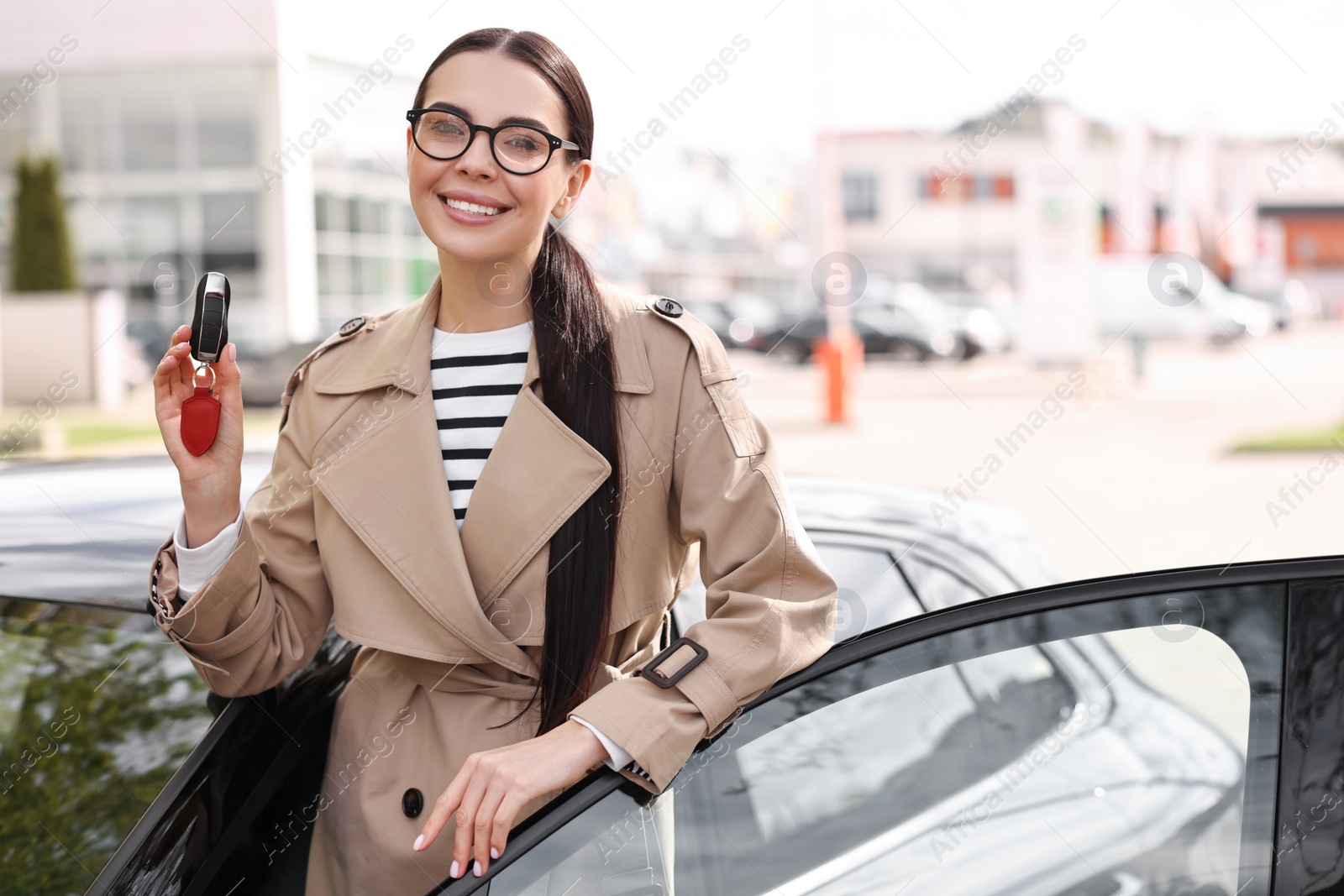 Photo of Woman holding car flip key near her vehicle outdoors