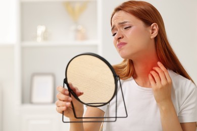 Photo of Suffering from allergy. Young woman looking in mirror and scratching her neck at home, space for text
