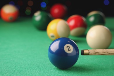 Photo of Billiard ball with number 2 and cue on green table