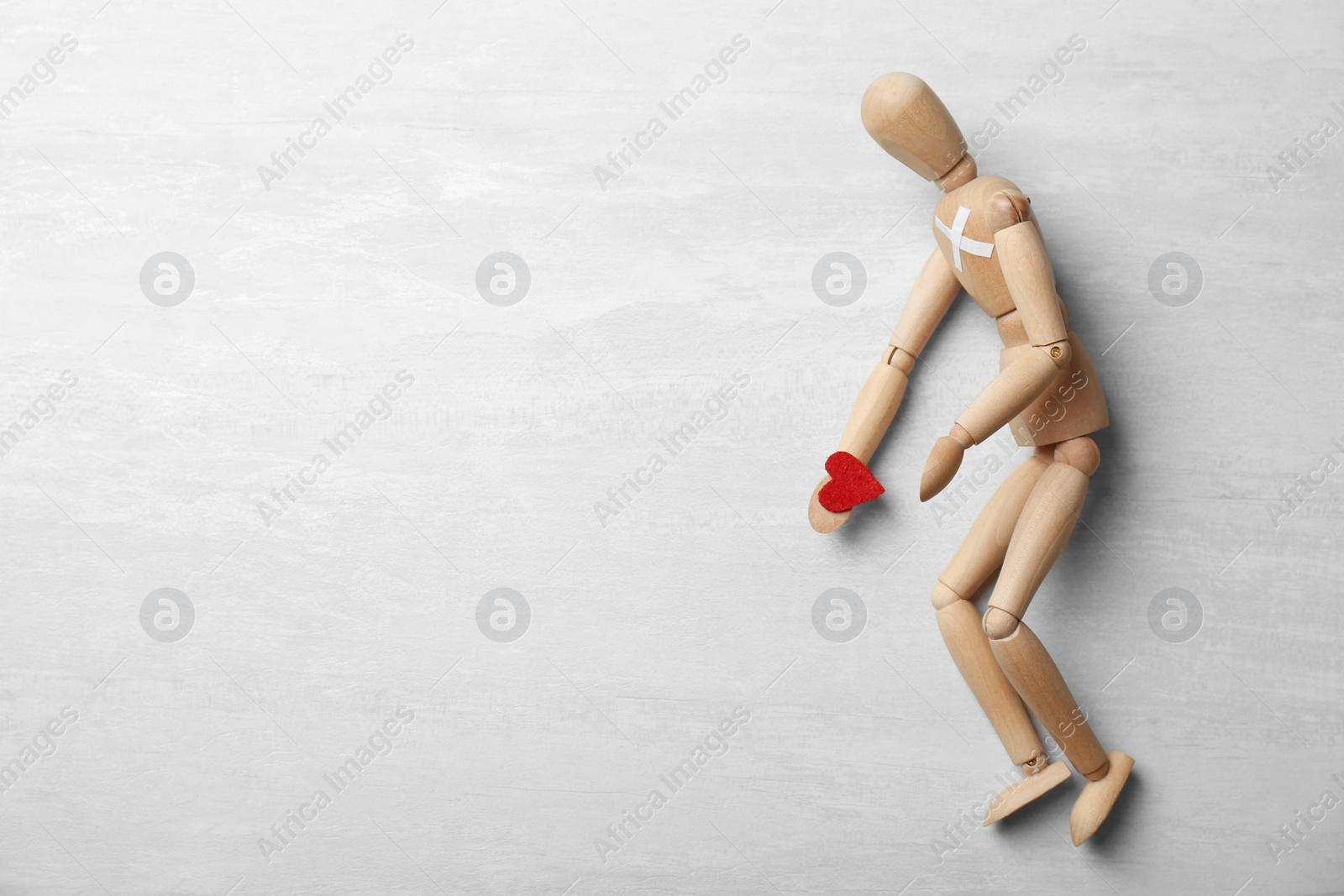 Photo of Wooden puppet holding small heart on gray background, top view with space for text. Relationship problems
