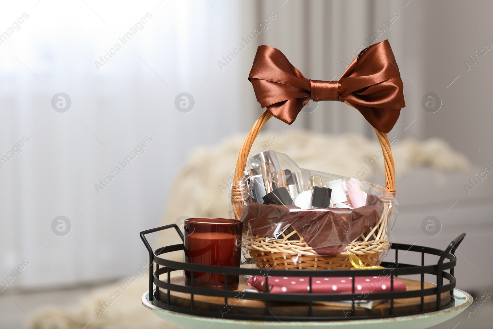 Photo of Wicker basket full of gifts on table in living room. Space for text