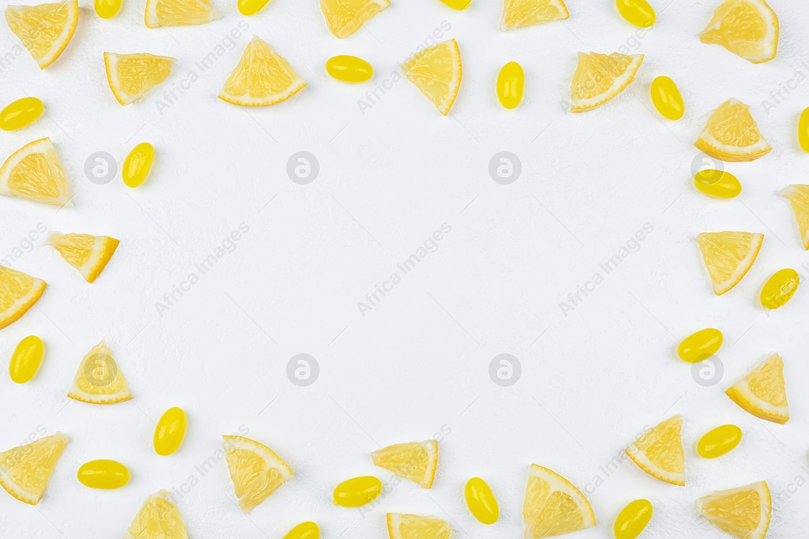 Photo of Frame made with fresh lemon slices and tasty candies on white table, flat lay. Space for text