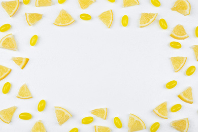 Photo of Frame made with fresh lemon slices and tasty candies on white table, flat lay. Space for text