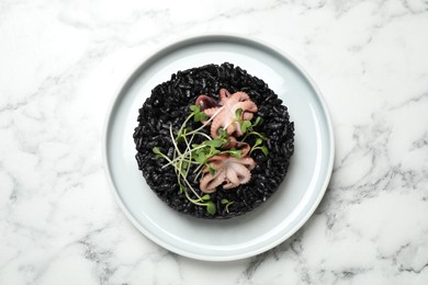 Photo of Delicious black risotto with seafood on white marble table, top view