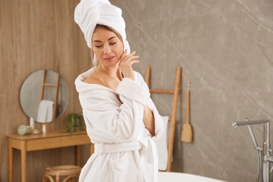 Photo of Beautiful woman wearing white bathrobe at home