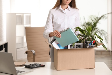 Photo of Upset young woman packing stuff in box at office