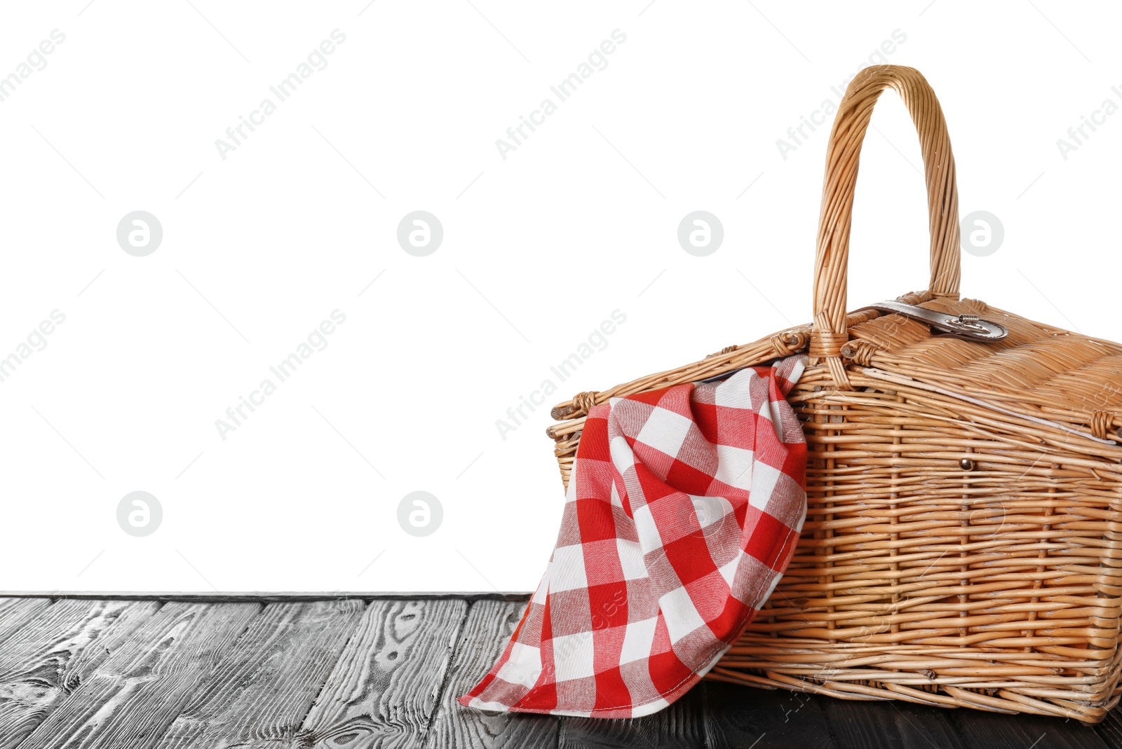 Photo of Closed wicker picnic basket with checkered tablecloth on wooden table against white background