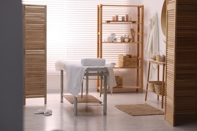 Comfortable massage table with clean towels in spa center