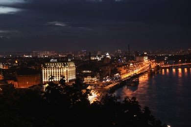 KYIV, UKRAINE - MAY 21, 2019: Beautiful view of night city with illuminated Fairmont Grand Hotel and other buildings near river