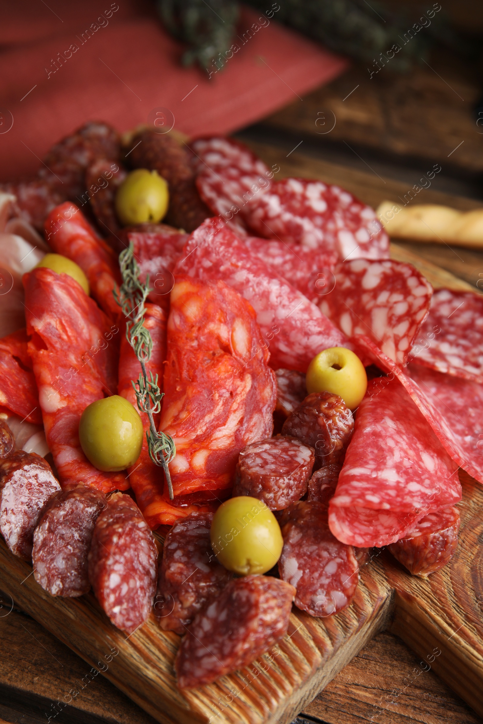 Photo of Tasty salami with other delicacies served on wooden table