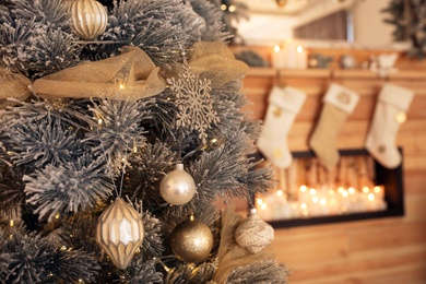 Beautiful decorated Christmas tree near fireplace. Festive interior