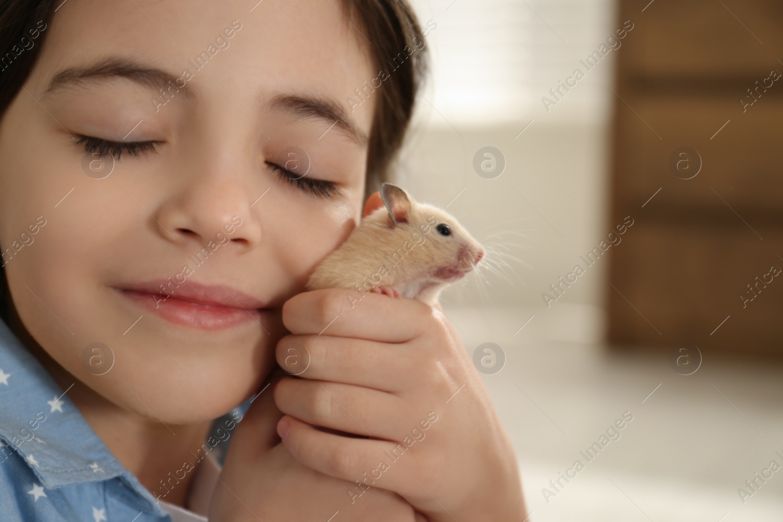 Photo of Little girl hugging cute hamster at home, closeup