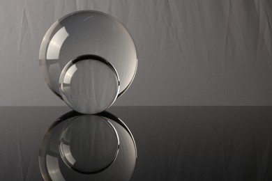 Transparent glass balls on mirror surface against light background. Space for text