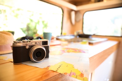 Photo of World map and vintage camera on wooden table in motorhome, space for text. Summer trip